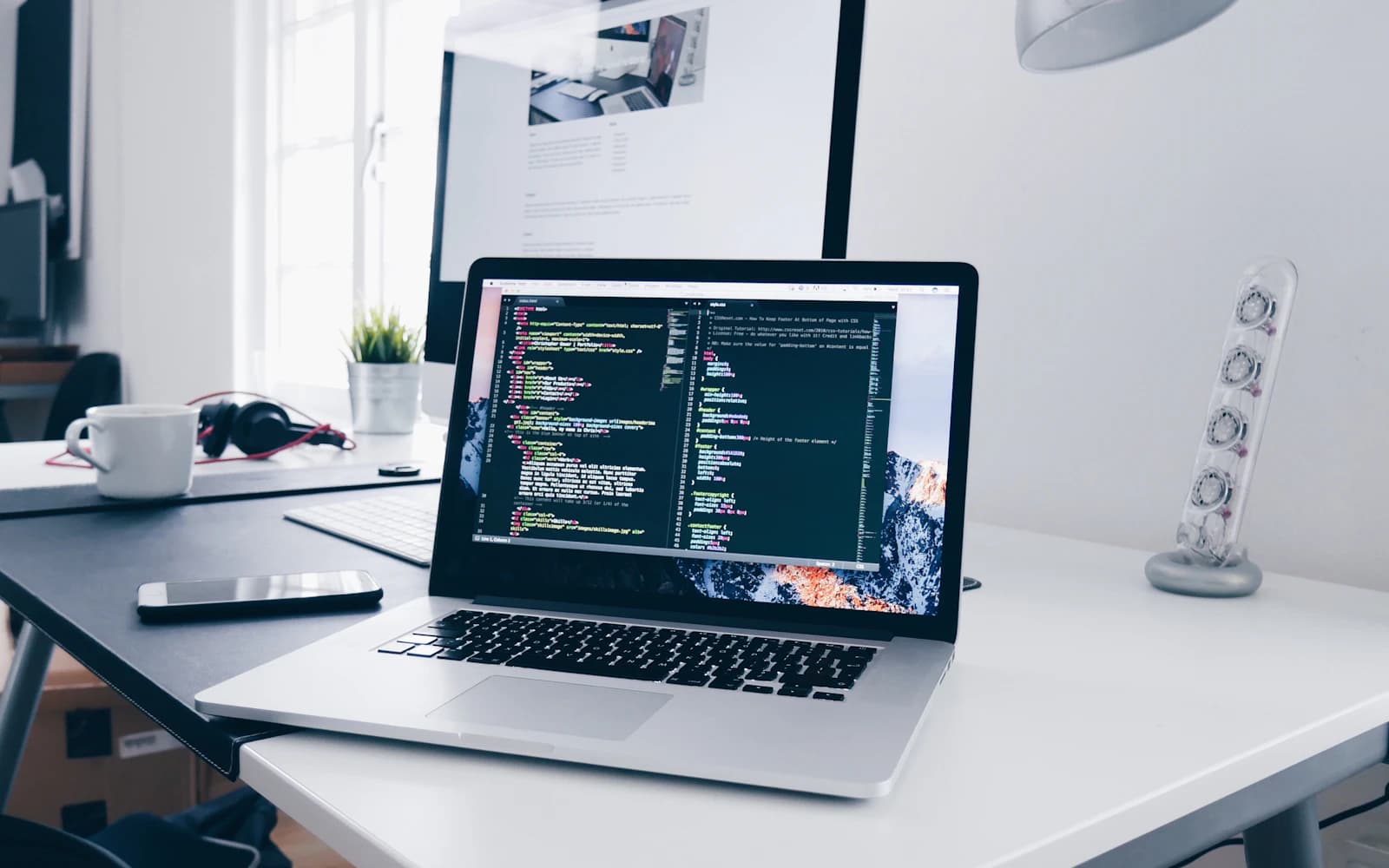 Laptop showing source code on a tidy white desk